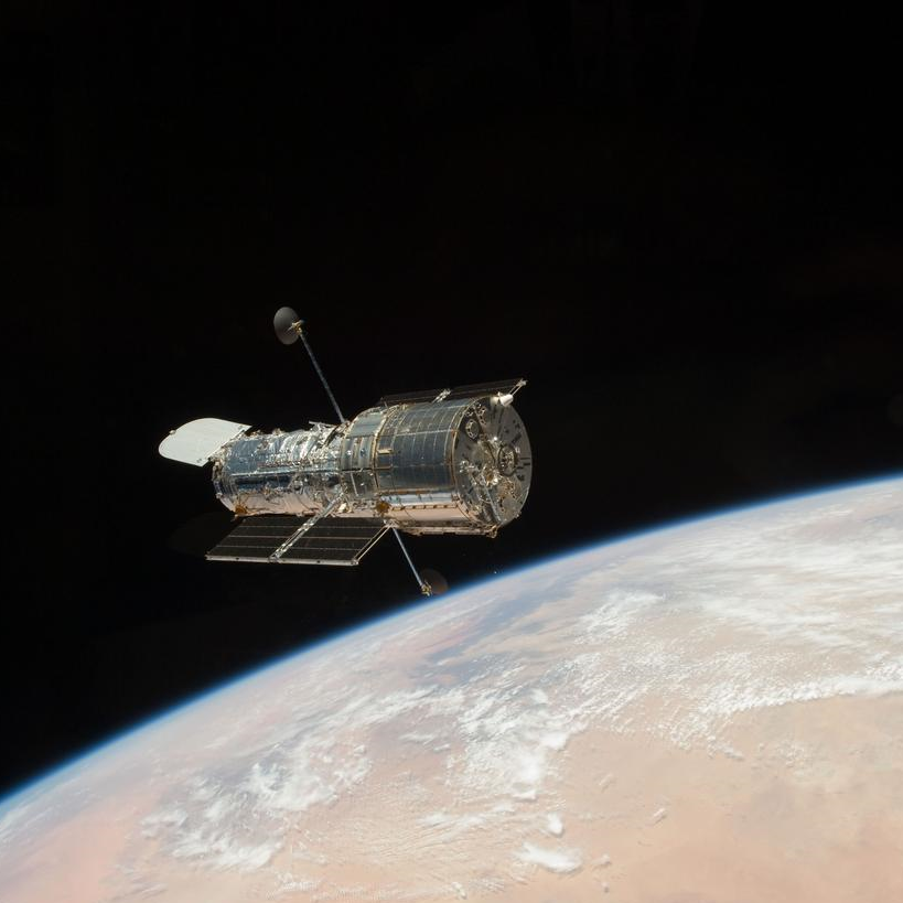The Hubble Space Telescope floats above an unknown planet.
