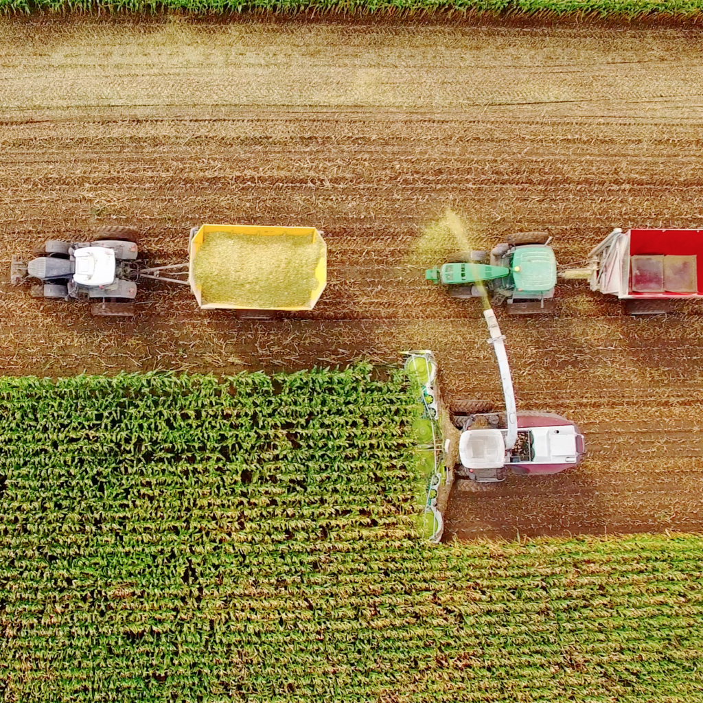 A bird's eye view of tractors and combines working in a farm field.