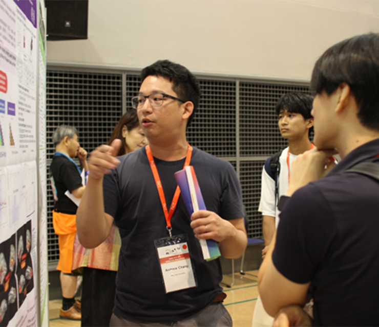 A postdoc presents his researcher and poster to conference attendees.