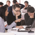 Researchers have a discussion while sitting at a computer.