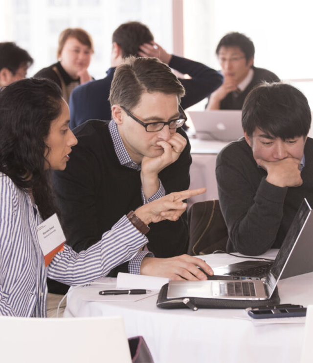 Researchers have a discussion while sitting at a computer.