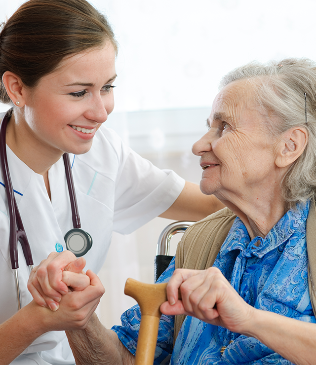 A healthcare works comforts an elderly patient.
