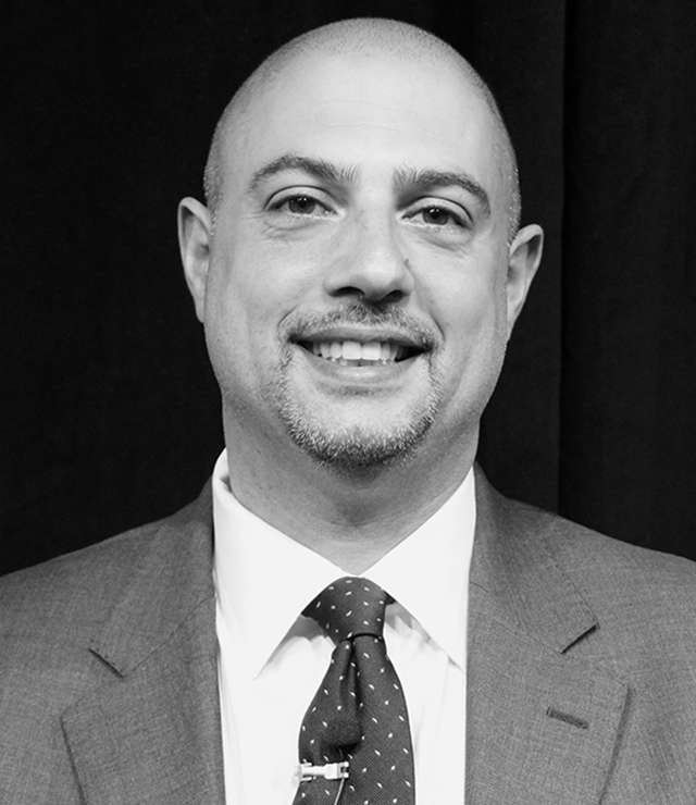 Sam Parnia smiles for the camera, wearing a suit and tie.