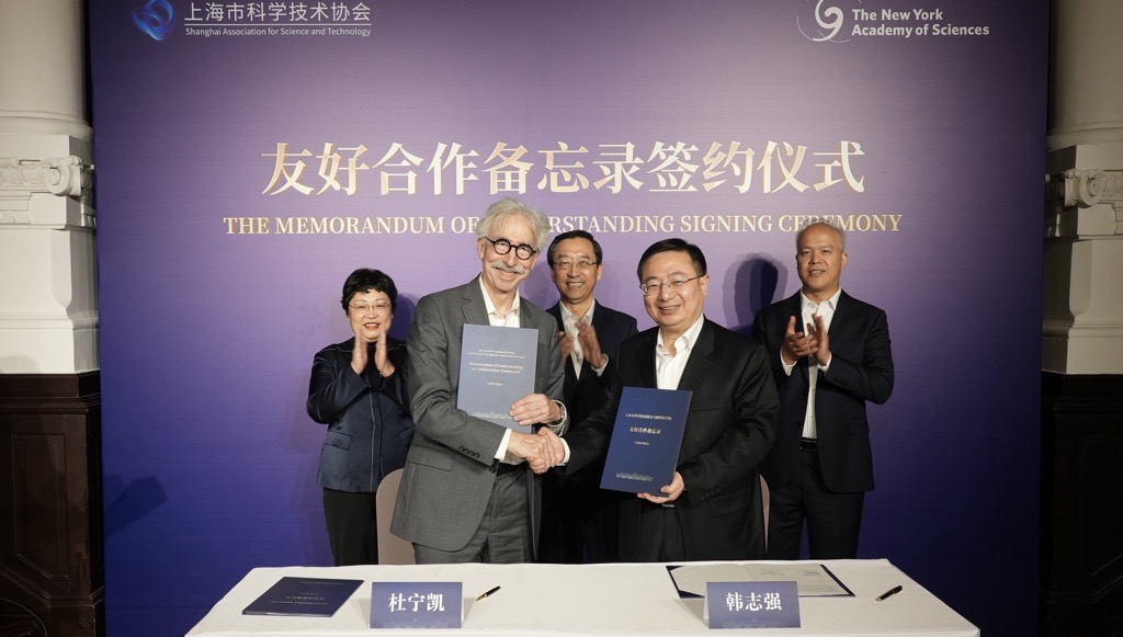 Two men shake hands after signing an agreement for future collaboration.