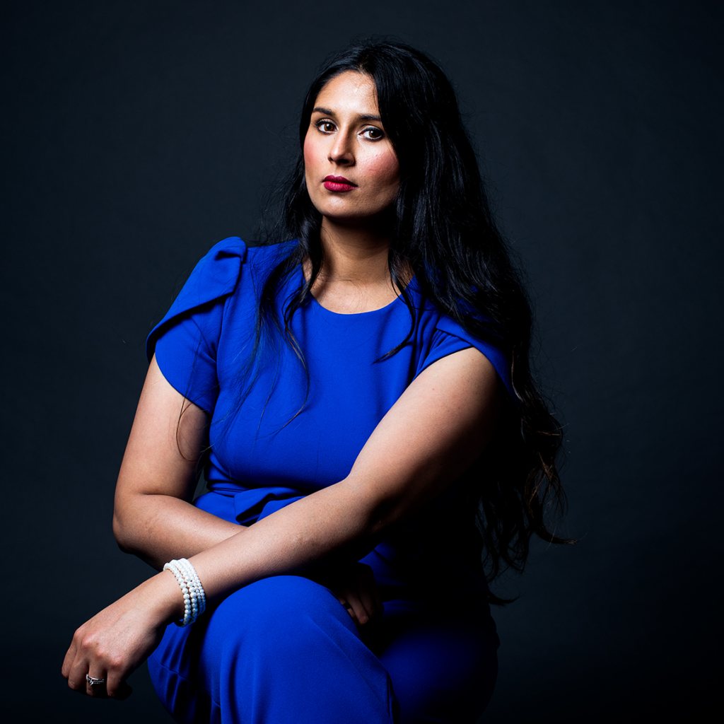 A woman in a blue dress poses for the camera.