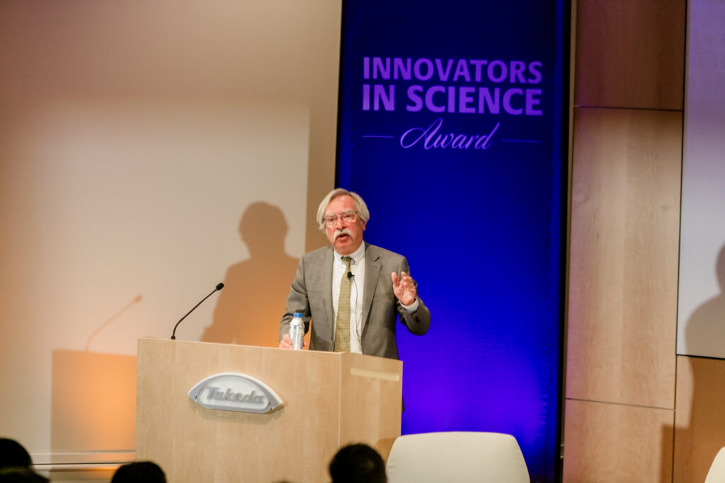 A man presents from the podium during the 2024 Innovators in Science Award symposium.