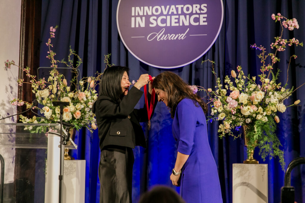 An award winner is presented with a medallion.