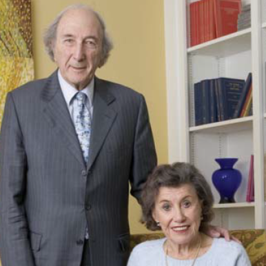 A couple pose together for the camera inside the study of their home.