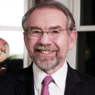 A man in a suit and tie smiles for the camera.