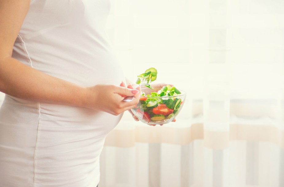 A pregnant woman eats a salad.