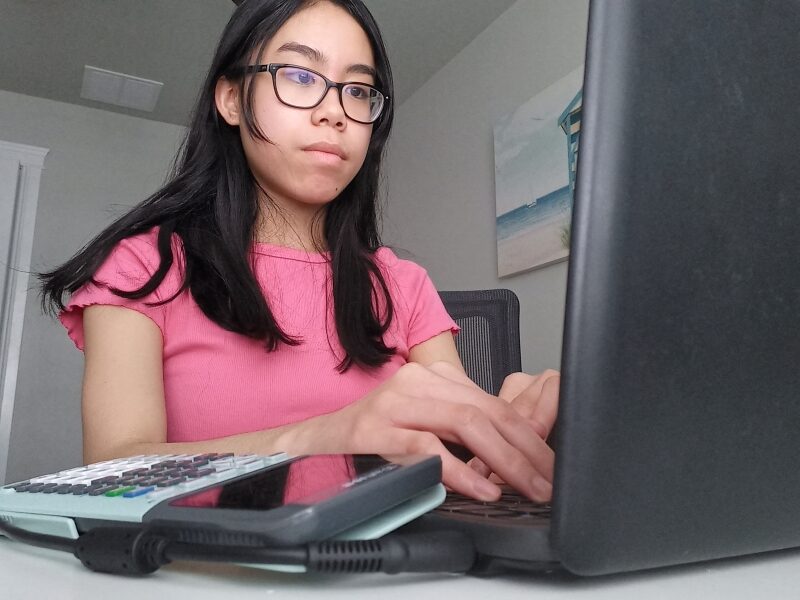 A Junior Academy participant sits at a desk, typing on a laptop.