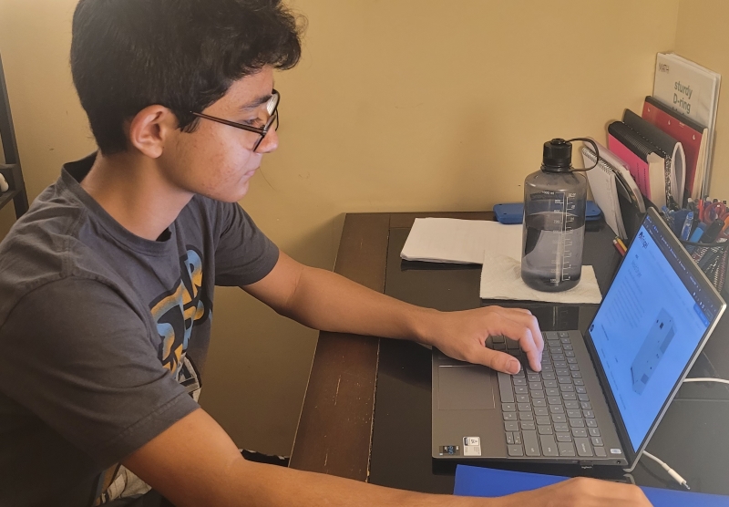 A Junior Academy participant sits at a desk, typing on a laptop.