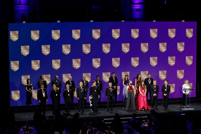 A large group of awardees pose on stage together.
