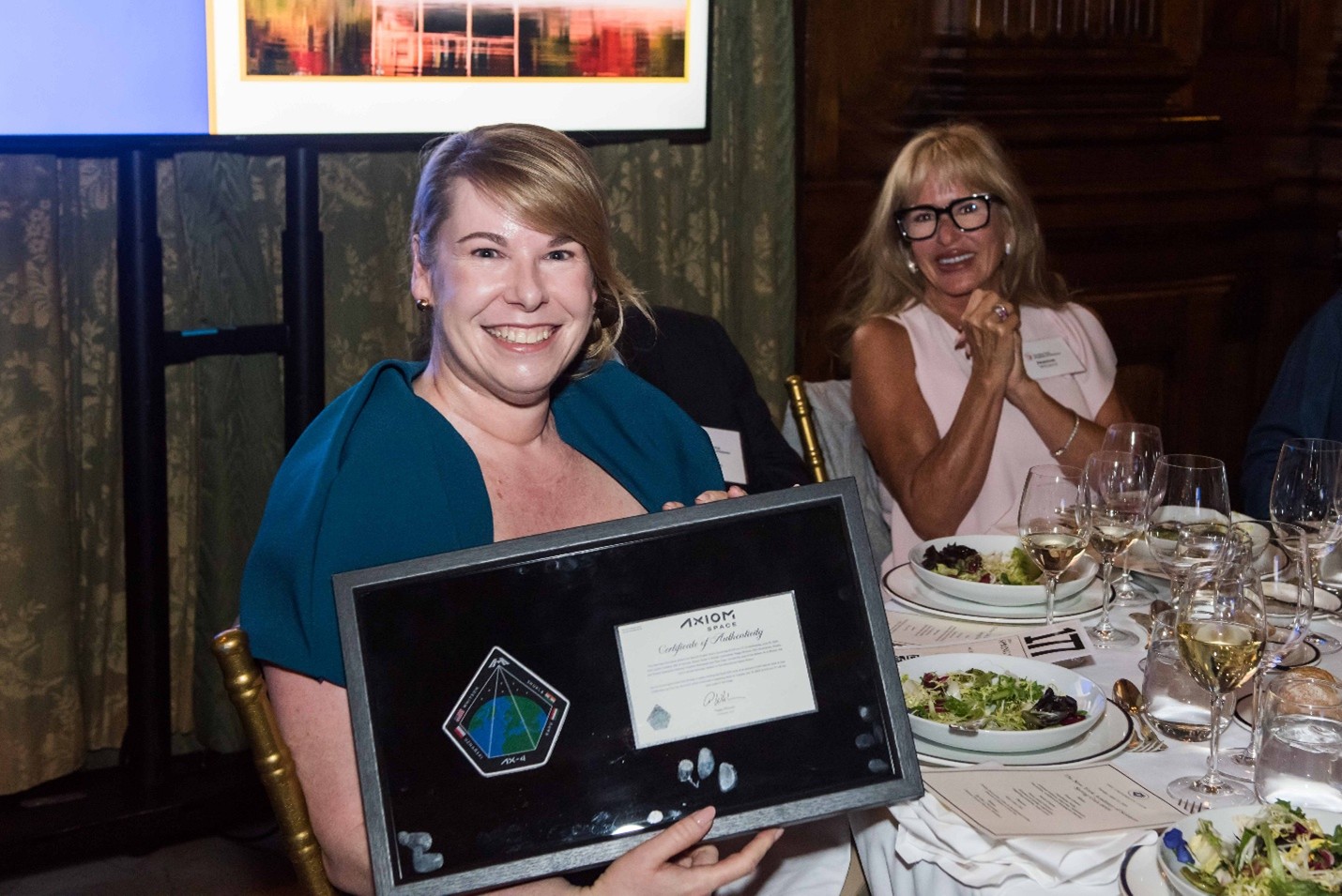 A woman poses with a framed space badge.