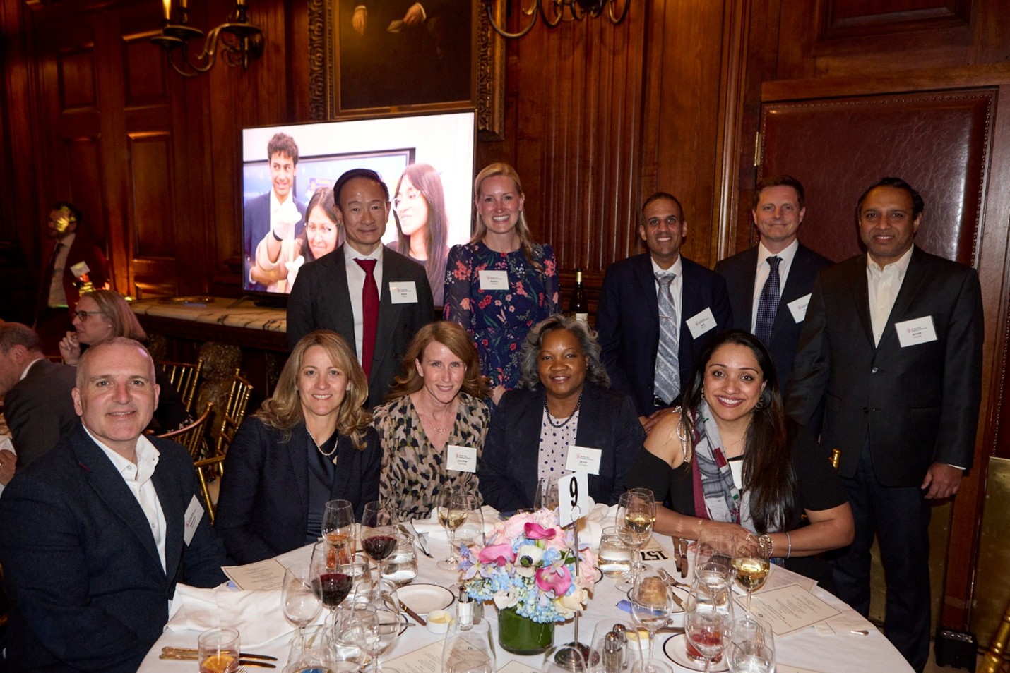 A group of formally dressed people pose at a dinner table together.