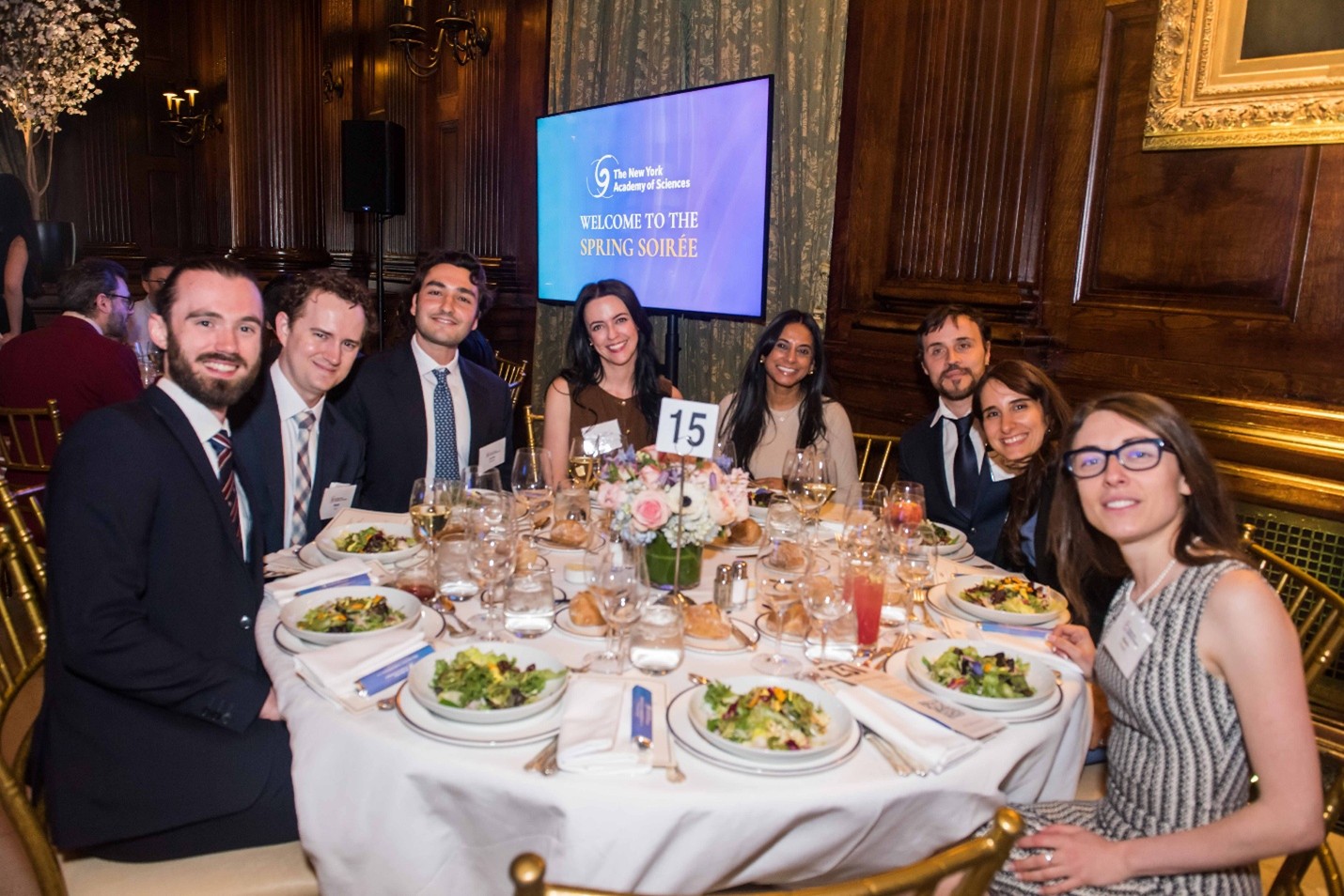 A group of formally dressed people sit at a dinner table together.