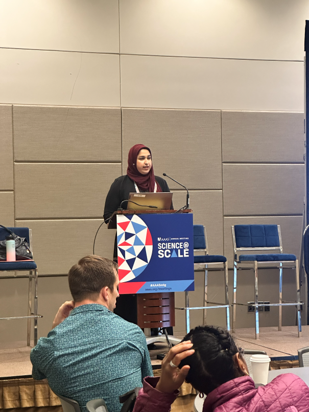 A lecturer stands at a podium and delivers an address.