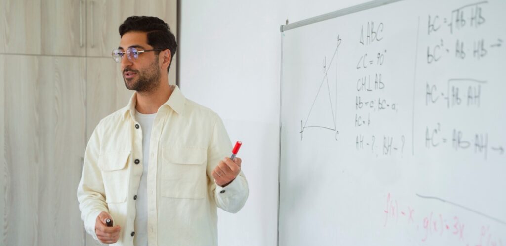 A man at a white board with mathematical equations.